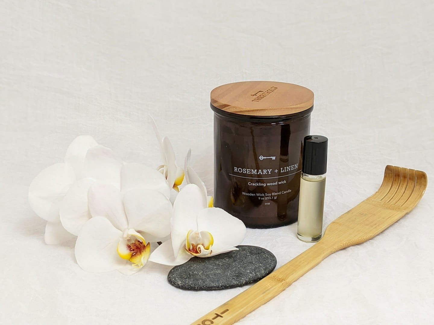 Produkty do spa ułożone z białą orchideą i kamieniem rzecznym.