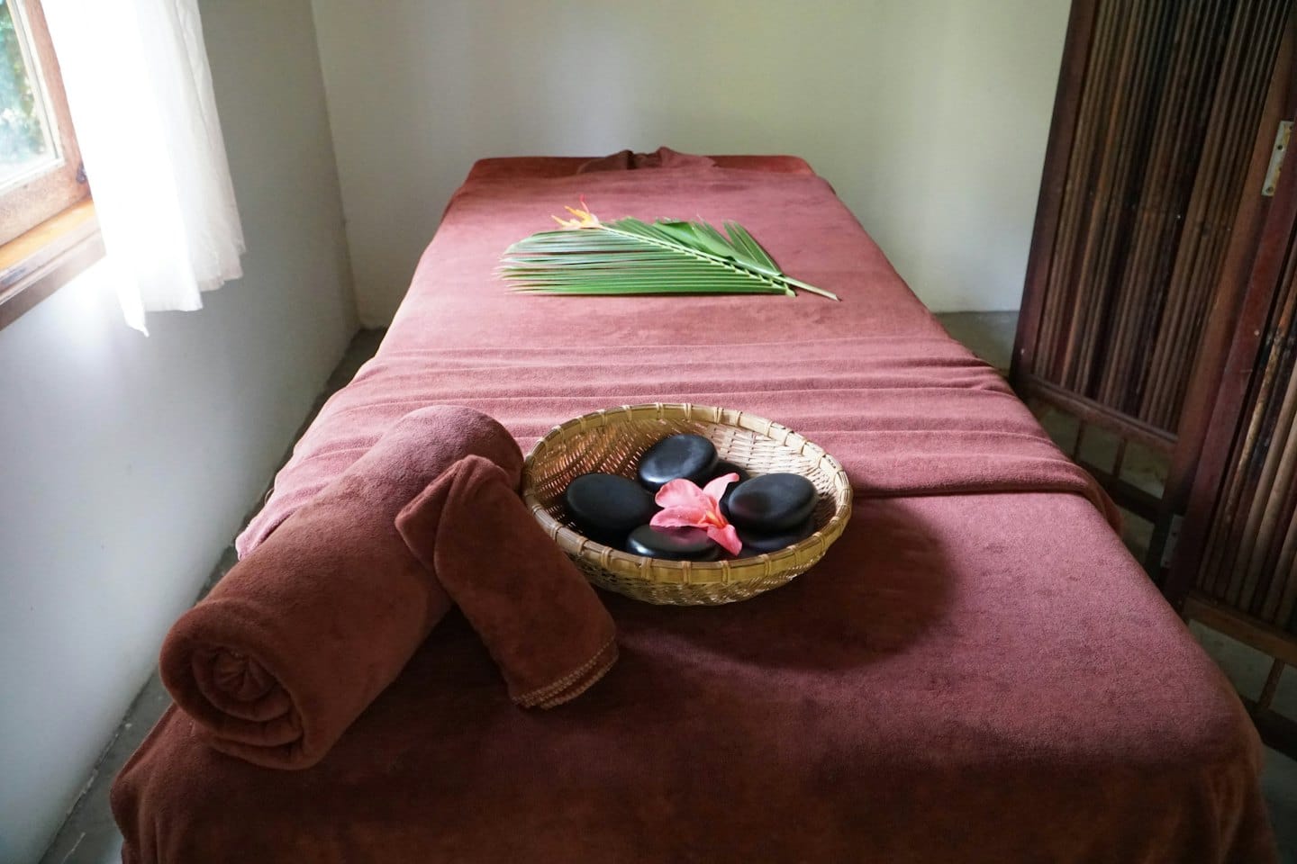 Łóżko do masażu z ręcznikami i kamieniami w pokoju spa.